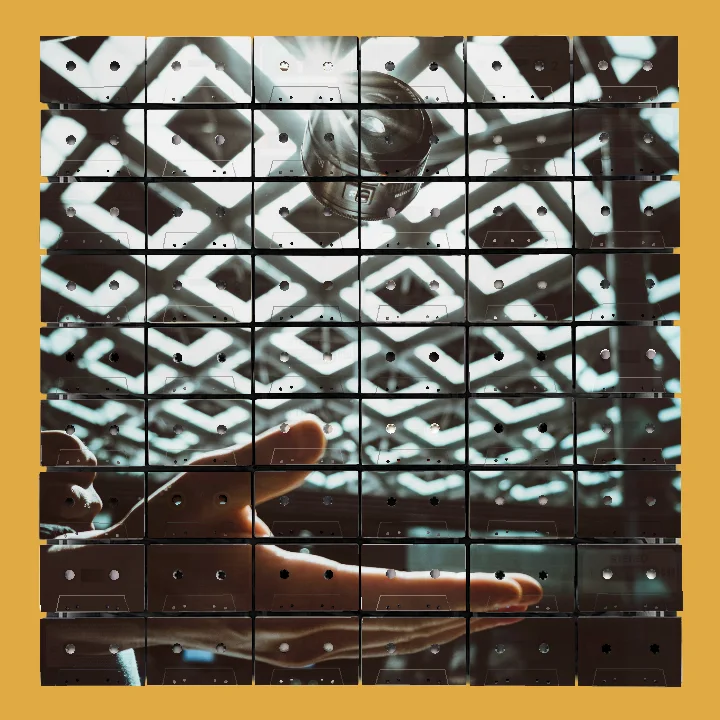 A person’s hand open upwards with a camera lens floating above it under a ceiling with square light panels.